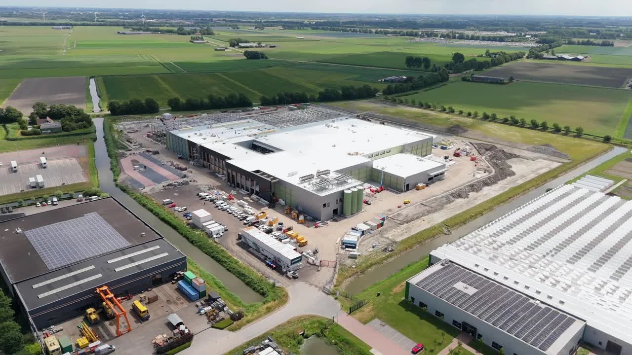 A large building under construction surrounded by fields, aerial view